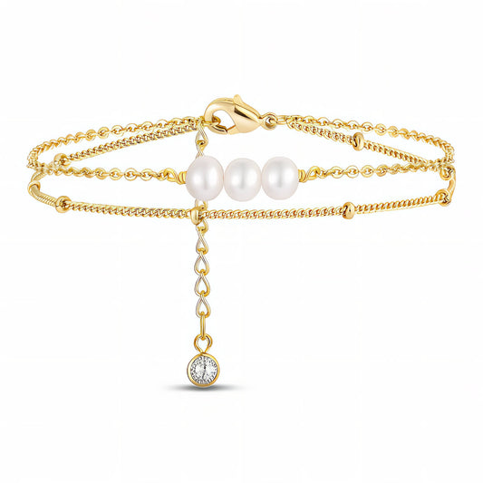 Gold bracelet with pearls and a small diamond on a white background